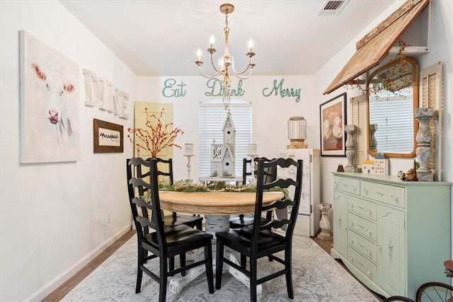 dining space with light wood-type flooring and an inviting chandelier