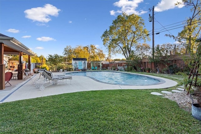 view of swimming pool featuring a lawn, a patio area, and a shed