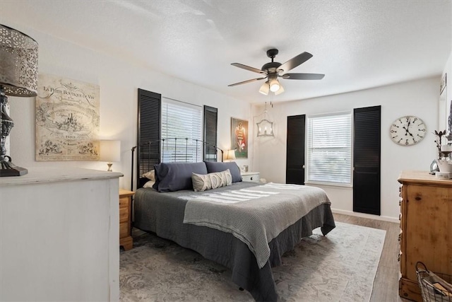 bedroom featuring ceiling fan, a textured ceiling, and light wood-type flooring