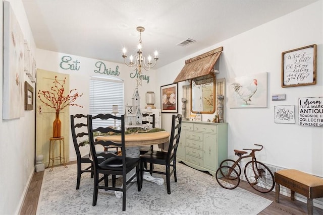 dining area featuring wood-type flooring and an inviting chandelier