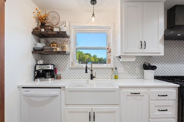 kitchen featuring tasteful backsplash, white dishwasher, wall chimney range hood, white cabinets, and hanging light fixtures