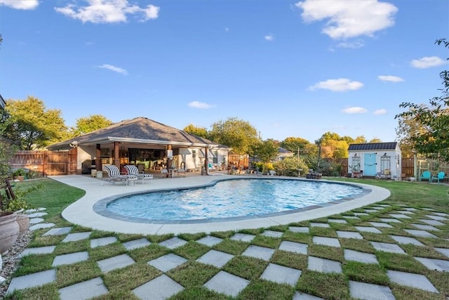 view of swimming pool with a patio, a shed, and a lawn