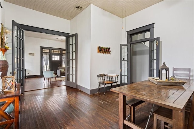 dining area featuring french doors, dark wood-type flooring, and a high ceiling