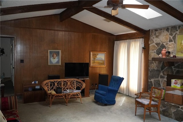 living area featuring wooden walls, carpet floors, a stone fireplace, and lofted ceiling with skylight