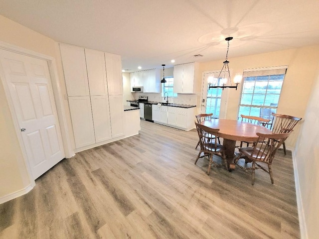 dining area featuring a notable chandelier, light hardwood / wood-style floors, and sink