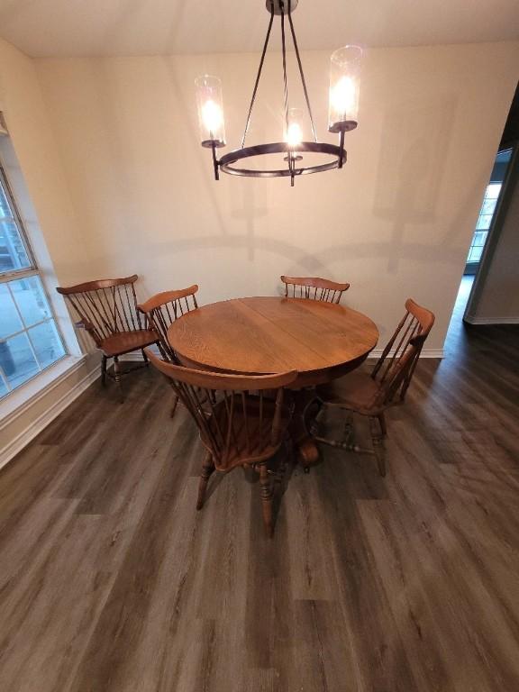 dining area with dark hardwood / wood-style floors and a notable chandelier