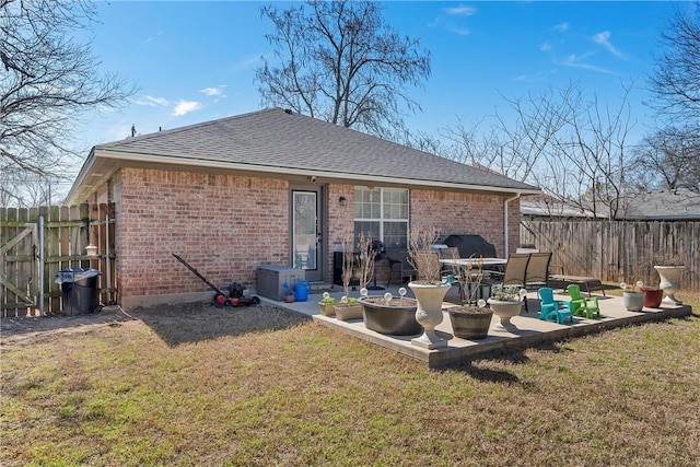 back of property featuring a patio, fence, a lawn, and brick siding