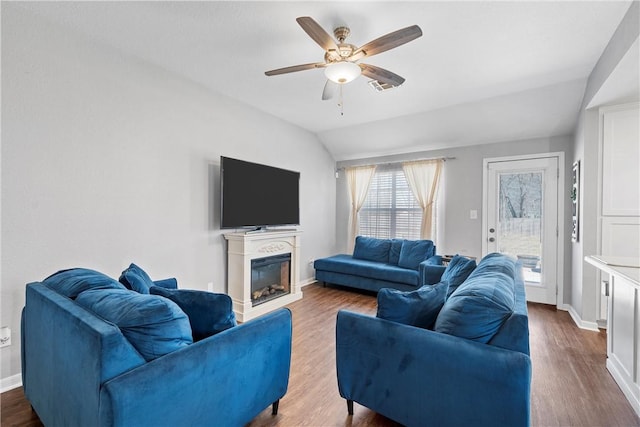 living room featuring lofted ceiling, a glass covered fireplace, dark wood finished floors, and ceiling fan