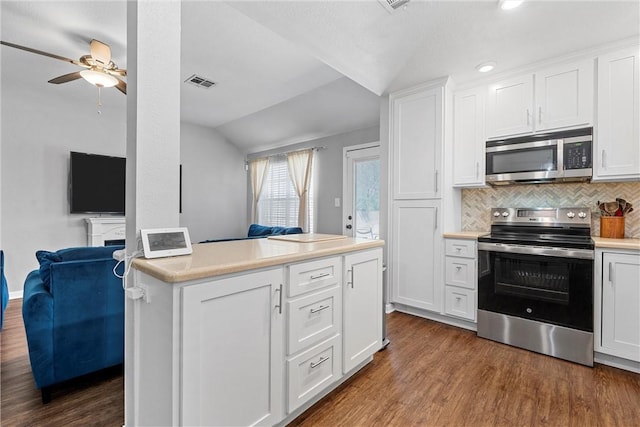 kitchen with appliances with stainless steel finishes, lofted ceiling, dark wood-style flooring, and decorative backsplash