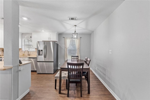 dining room featuring baseboards, a textured ceiling, visible vents, and dark wood-type flooring