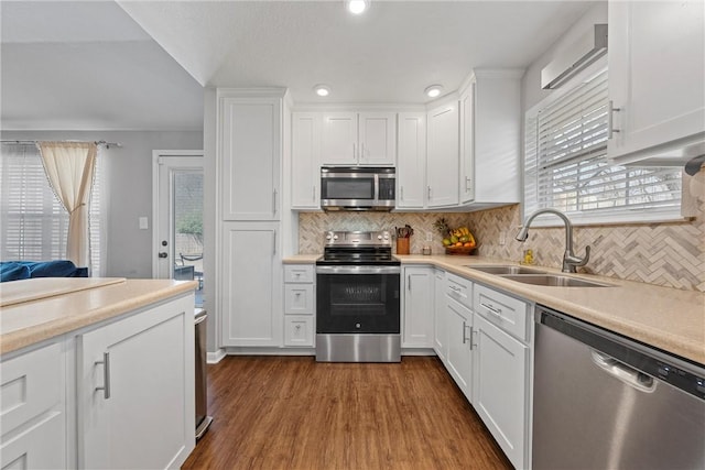 kitchen with appliances with stainless steel finishes, dark wood-style flooring, light countertops, white cabinetry, and a sink