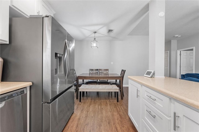 kitchen featuring stainless steel appliances, light wood finished floors, light countertops, and white cabinets