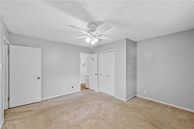 unfurnished bedroom featuring a closet, a textured ceiling, light colored carpet, and ceiling fan