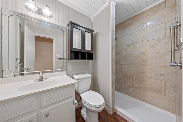 bathroom featuring vanity, crown molding, hardwood / wood-style flooring, toilet, and a tile shower