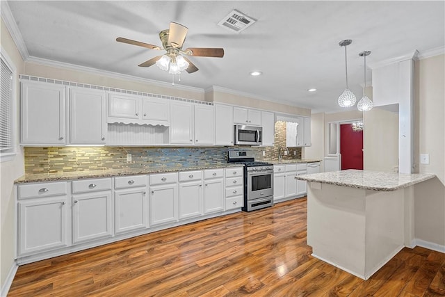 kitchen featuring white cabinetry, ceiling fan, stainless steel appliances, wood-type flooring, and decorative light fixtures