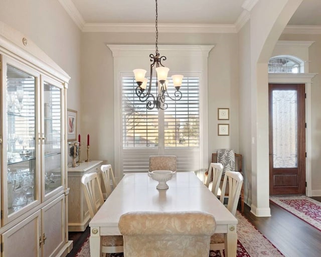 dining area featuring crown molding, dark wood-type flooring, and a chandelier