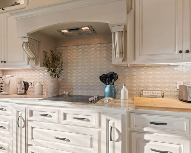 kitchen featuring backsplash, white cabinets, black electric cooktop, and range hood