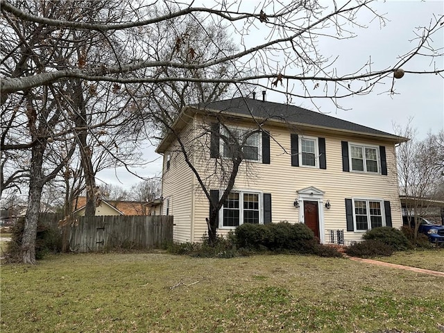 colonial home featuring a front lawn and fence