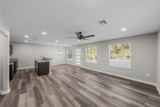 unfurnished living room with dark hardwood / wood-style flooring, ceiling fan, and sink