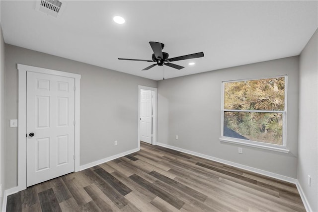 empty room with ceiling fan and dark hardwood / wood-style flooring