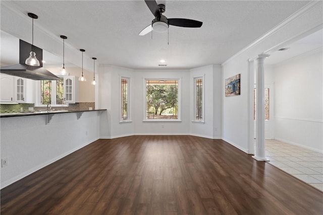 unfurnished living room with a textured ceiling, dark hardwood / wood-style flooring, ceiling fan, and crown molding