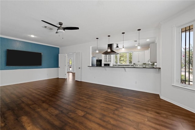 unfurnished living room with dark hardwood / wood-style flooring, a healthy amount of sunlight, and ornamental molding