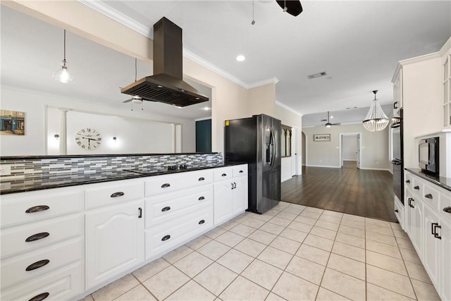 kitchen with ceiling fan, island range hood, black fridge, and white cabinetry