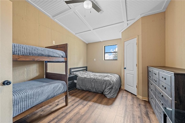 bedroom featuring dark hardwood / wood-style floors, ceiling fan, lofted ceiling, and wood walls