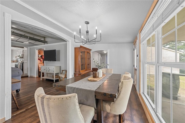 dining space featuring a textured ceiling, dark hardwood / wood-style floors, and a notable chandelier