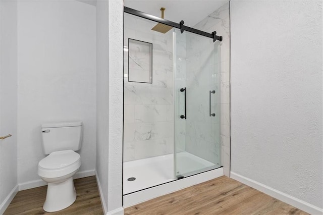 bathroom featuring wood-type flooring, toilet, and a shower with shower door