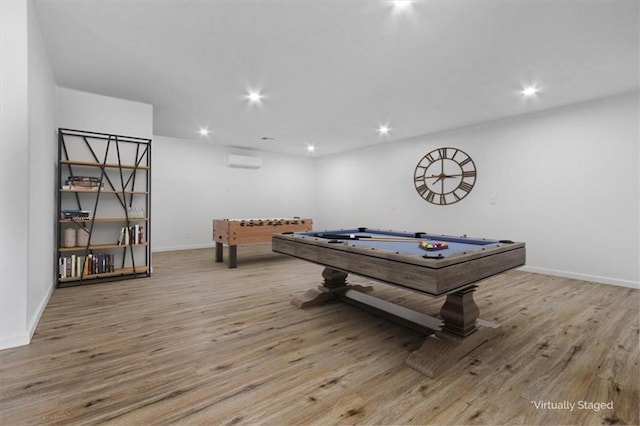 recreation room with a wall unit AC and light hardwood / wood-style floors