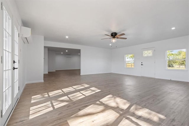 interior space featuring hardwood / wood-style flooring, a wall mounted AC, and ceiling fan