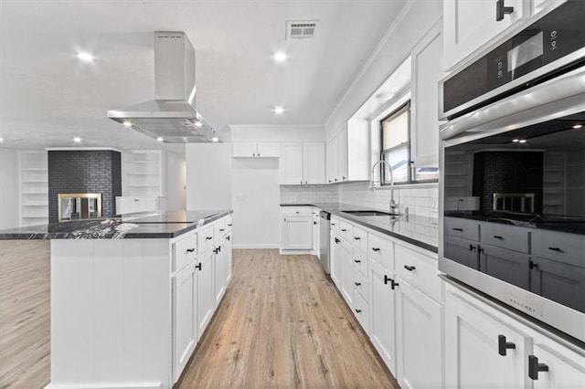 kitchen featuring sink, stainless steel appliances, island range hood, white cabinets, and a kitchen island