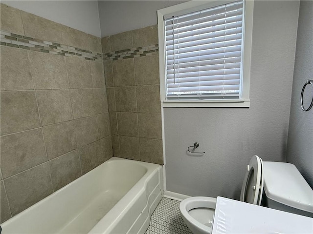 bathroom with tiled shower / bath, a healthy amount of sunlight, toilet, and tile patterned flooring