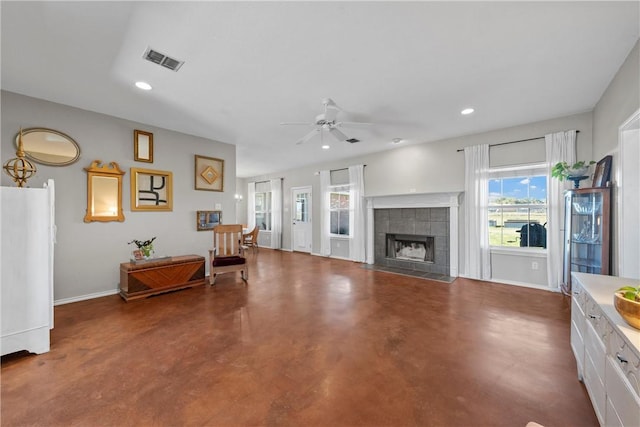 living area with concrete floors, a tiled fireplace, visible vents, and recessed lighting