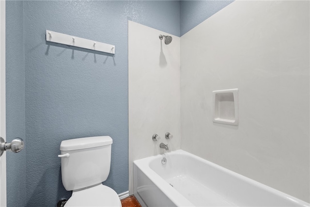 bathroom featuring toilet, shower / bathtub combination, and a textured wall