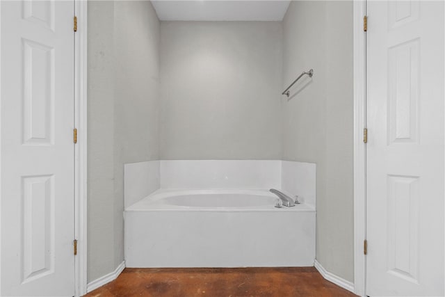 bathroom with concrete flooring and a bath