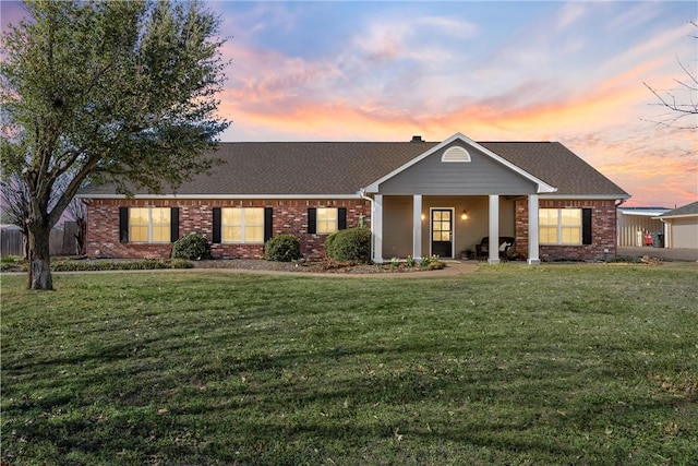 view of front of home featuring brick siding, a front lawn, and a shingled roof