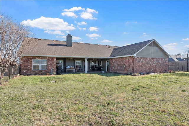 rear view of house with a chimney, brick siding, a lawn, and a fenced backyard