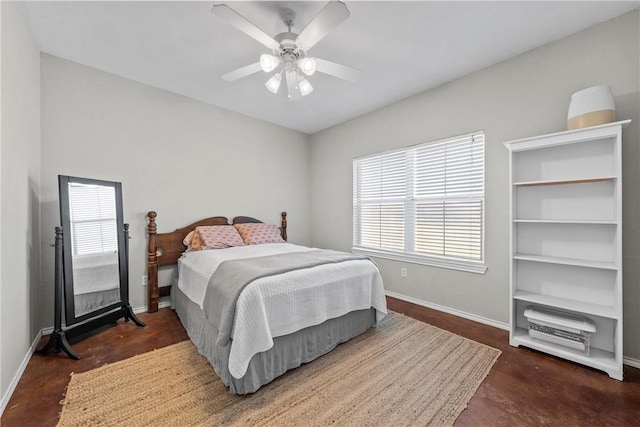 bedroom featuring finished concrete flooring, a ceiling fan, and baseboards