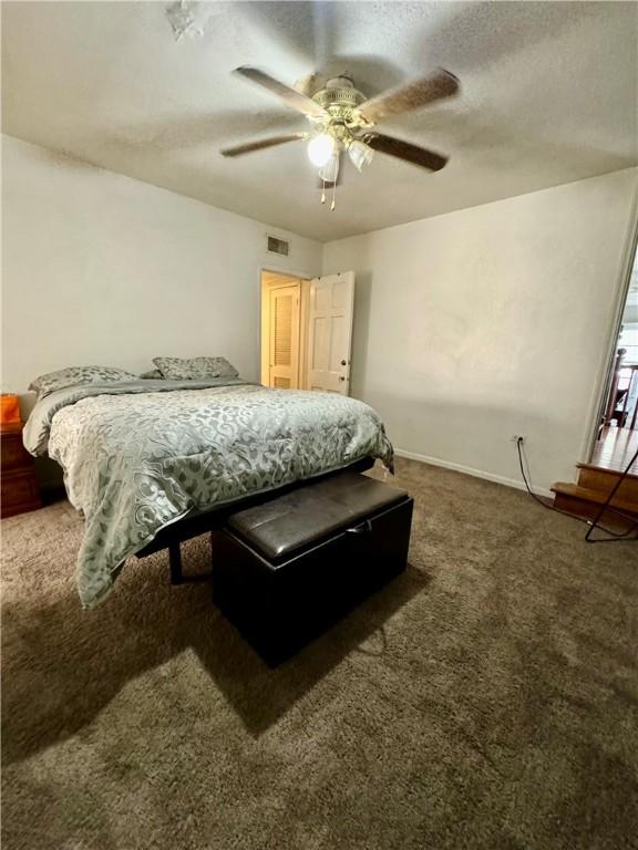 carpeted bedroom with ceiling fan and a textured ceiling