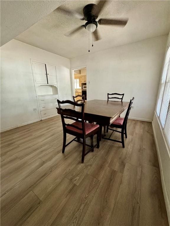 dining space featuring a textured ceiling, ceiling fan, and dark wood-type flooring