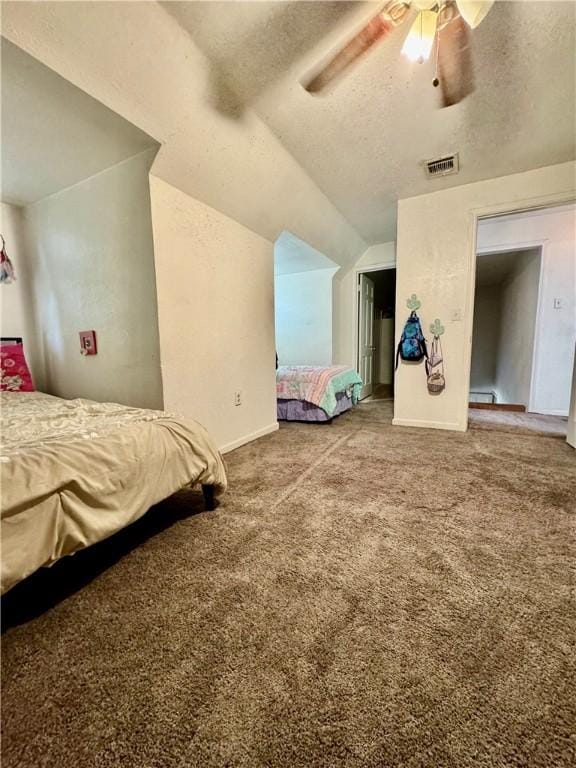 bedroom with a textured ceiling, ceiling fan, carpet floors, and vaulted ceiling