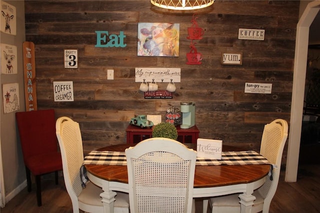 dining room featuring hardwood / wood-style flooring and wooden walls