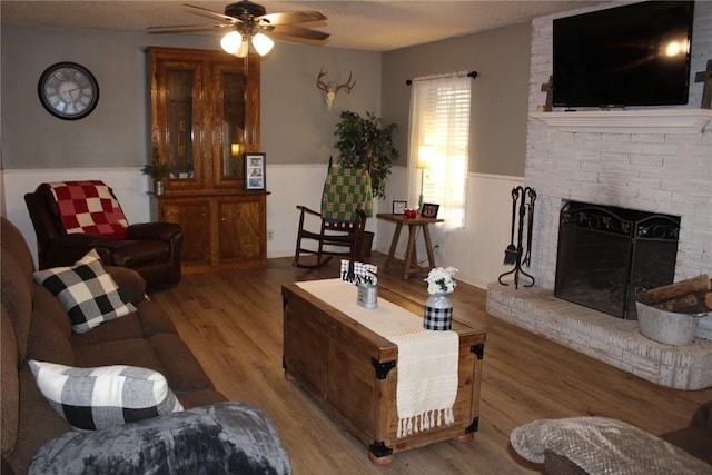 living room with ceiling fan, a fireplace, and light hardwood / wood-style flooring