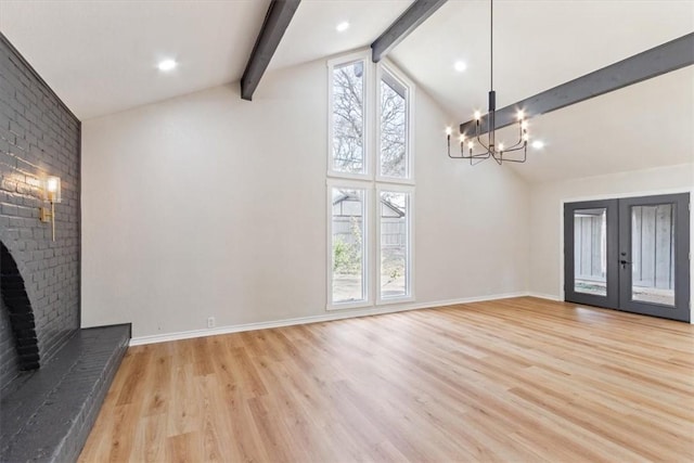 unfurnished living room featuring french doors, a brick fireplace, beam ceiling, light hardwood / wood-style flooring, and a chandelier