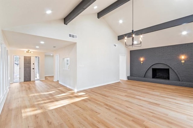 unfurnished living room with high vaulted ceiling, beamed ceiling, a notable chandelier, a fireplace, and light hardwood / wood-style floors