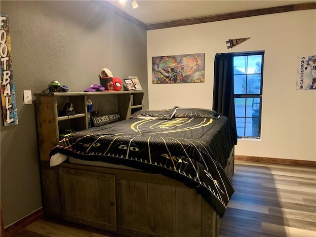 bedroom with crown molding, wood finished floors, and baseboards