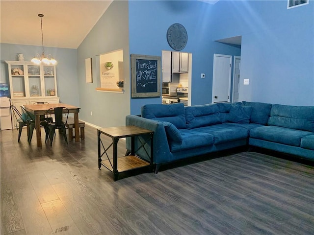 living area with dark wood finished floors, a notable chandelier, baseboards, and high vaulted ceiling