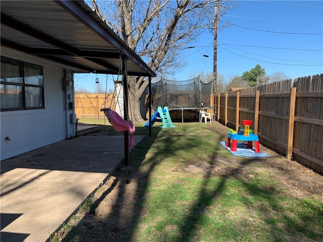 view of yard featuring a trampoline, a fenced backyard, and a patio area